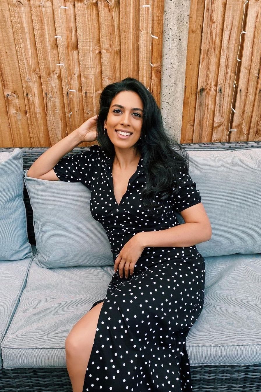 Crystelle Pereira smiling, seated on a garden sofa